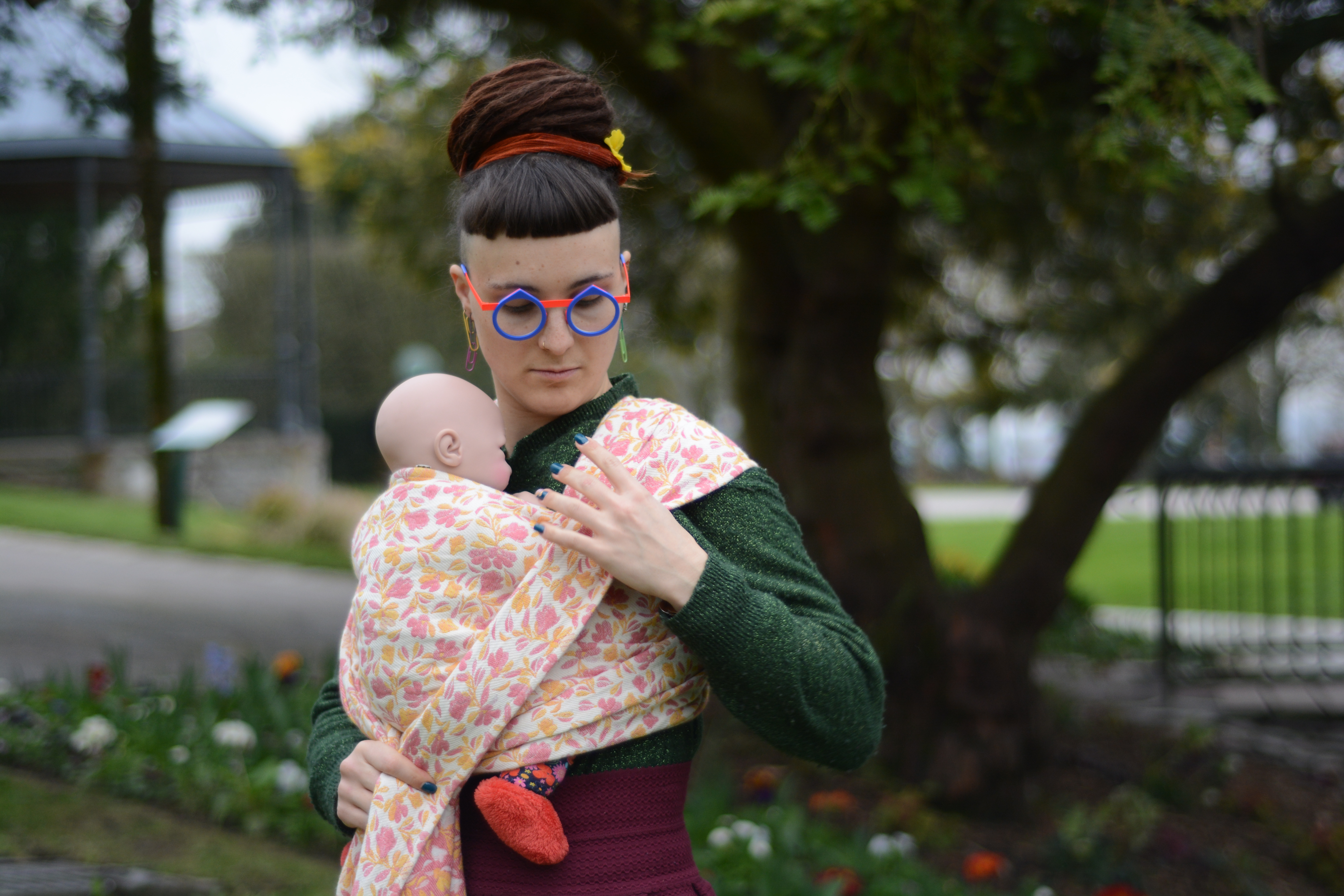 Une femme est entrain de nouer son écharpe avec un poupon de portage